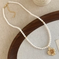 Detalle de un collar de perlas con colgante de flor de cristal dorado estilo retro - Flor Amarilla