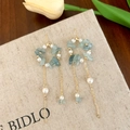 Détails de boucles d'oreilles pompons en pierre bleu clair et perles sur carte en lin - Boucles d'oreilles à pompon bleu
