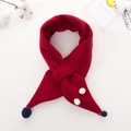 Dettaglio di una sciarpa in maglia rossa per bambini con pompon blu e decorazioni - Borgogna