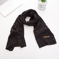 Dettaglio di sciarpa in maglia nera con etichetta in pelle marrone e trama morbida - Nero