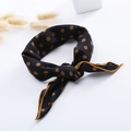 Dettaglio di un foulard in raso a pois neri e marroni annodato con cura su uno sfondo bianco - Pois Neri