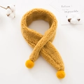 Detailed texture of yellow plush scarf with soft pom-poms for children winter warmth - Turmeric