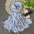 Primo piano di sciarpa celeste con piccoli quadri marroni e bordi con nappine - Blu
