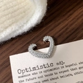 Macro di un ear cuff a cuore in argento con zirconi su una carta dallo stile vintage - Polsino per Orecchie Cuore Argento