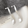 Macro-opname van matzilveren gedraaide oorringen met een minimalistisch industrieel design - Lange Oorknopjes / Zilver