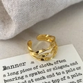 Detail of a gold layered twisted geometric open ring with polished metal texture - Gold