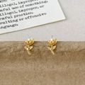 Dettaglio di eleganti orecchini a tulipano dorati con perla bianca su carta kraft - Tulipano Oro