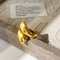 Detail of high-polish gold fluid-style ring on geometric textured base with artistic lighting - Gold Ring / Gold