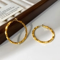 Vista dettagliata di grandi orecchini a cerchio dorati martellati su supporto espositivo - Oro-4cm