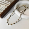 Dettaglio della collana con perle e occhio di tigre con chiusura dorata su ceramica - Collana di Perle Occhio di Tigre