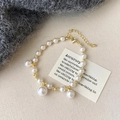 Detailed close-up of pearl necklace with gold beads on an elegant fabric background - Bracelet / Gold/White