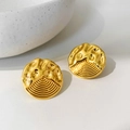 Makroaufnahme goldener unregelmäßiger Ohrringe mit Hammerschlag und radialen Linien - Gold