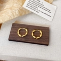 Close-up of gold beaded hoop earrings on a wooden stand with a minimalist warm aesthetic - Gold