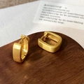 Close-up of golden geometric rectangle earrings with brushed matte finish on wood - Gold