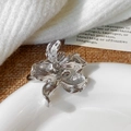 Dettaglio di un anello a fiore d'argento con petali spazzolati su uno sfondo di lino - Argento