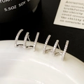 Detail shot of silver claw stud earrings with micro-set zircons on white ceramic - Silver