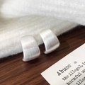 Macro shot of silver C-shaped earrings with brushed metallic texture on white fabric - Silver Brushed Stud Earrings