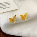 Makroaufnahme goldener Schmetterlingsohrringe mit Matt-Effekt auf weißem Strickstoff - Gold