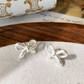 Détail de boucles d'oreilles nœuds en argent mat avec une finition sablée texturée - Noeud Papillon Mat / Argenté