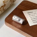 Dettaglio macro di charm cilindrico d'argento con finitura a specchio lucido su legno - Argento