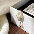 Dettaglio dell'ear cuff dorato multistrato con perle e pendente a cuore su portagioie - Oro
