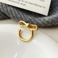 Primo piano di un delicato ear cuff a fiocco dorato senza buco su ceramica bianca - Oro