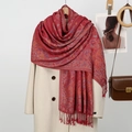 Détail d'une écharpe jacquard paisley rouge avec franges et manteau en laine beige - Bordeaux