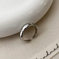 Detail van zilveren verstelbare ring met drie kiezelvormige accenten op keramische plaat - Zilver