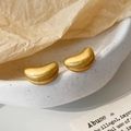 Dettaglio degli orecchini a fagiolo in oro spazzolato su una ciotola di ceramica - Oro