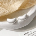 Dettaglio degli orecchini a lobo in argento spazzolato a forma di fagiolo su ceramica - Argento