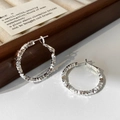 Dettaglio macro di orecchini a cerchio irregolari in argento con finitura testurizzata - Argento-3cm
