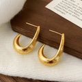 Detail goldener U-förmiger Ohrringe mit gebürsteter Textur auf einer Holzkarte - Gold Texturierte Ohrstecker