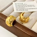 Dettaglio di orecchini a cerchio intrecciati dorati su un vassoio di velluto - Oro