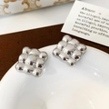 Detail of silver square earrings with quilted texture on a white ceramic dish - Silver