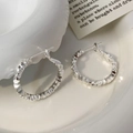 Detailed close-up of silver irregular textured earrings in a white ceramic dish - Silver-2.5cm