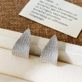 Nahaufnahme von silbernen Dreieck-Ohrsteckern mit weißen Kristallen in einer Schmuckbox - Pave-Zirkonia-Stil / Silber