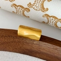 Macro detail of golden cylindrical metal ear cuff showing textured brushed finish - Gold