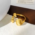 Macro shot of gold adjustable ring featuring seashell and conch textures on warm background - Gold