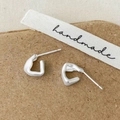 Macro detail of matte silver irregular geometric earrings with S925 hallmark on brown paper - Silver Stud Earrings