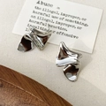 Macro shot of silver irregular pleated earrings with minimalist fold design and polished finish - Wrinkled Studs / Silver