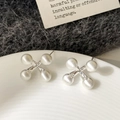 Macro detail of geometric X-shaped earrings with matte silver beads on ceramic tray - Silver Brushed Stud Earrings