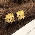 Detail of gold zircon earrings with wrinkled texture and hollow mesh on brown fabric - Gold