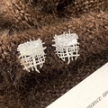 Macro detail of silver geometric mesh earrings on dark textured fabric background - Silver