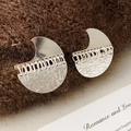 Detailaufnahme silberner geometrischer Ohrringe mit Kettenfransen auf Strickstoff - Silber