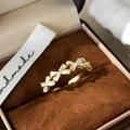 Detailed close-up of a gold bow ring with green zircon stones in a plush gift box - C-137 Row Bow Style (C-137) / Green