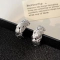 Dettaglio di orecchini a cerchio intrecciati argento su scatola nera elegante - Orecchini a perno intrecciati argento / Argento