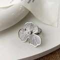 Detalle de anillo de flor plateada con pétalos texturizados y un circón brillante - Plateado