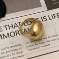 Detailed view of an exaggerated polished gold egg-shaped geometric ring on a newspaper - Gold Mirror Thickened Oval Ring (C-217)