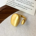 Detailed side view of golden brushed metal ring featuring a matte oval dome design - Gold