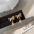 Detailansicht goldener Schleifen-Perlenohrringe auf Display mit handgefertigter Ästhetik - Gold